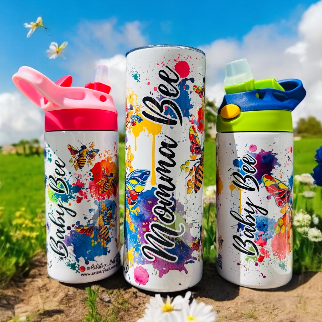 A set of three insulated sippy cups with colorful splatter paint designs and bee-themed decorations, each with different colored lids.
