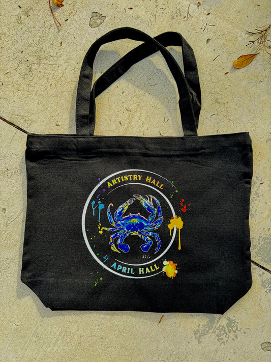 Black tote bag with Blue Crab design with the name "Artistry Hall" & artist "April Hall"