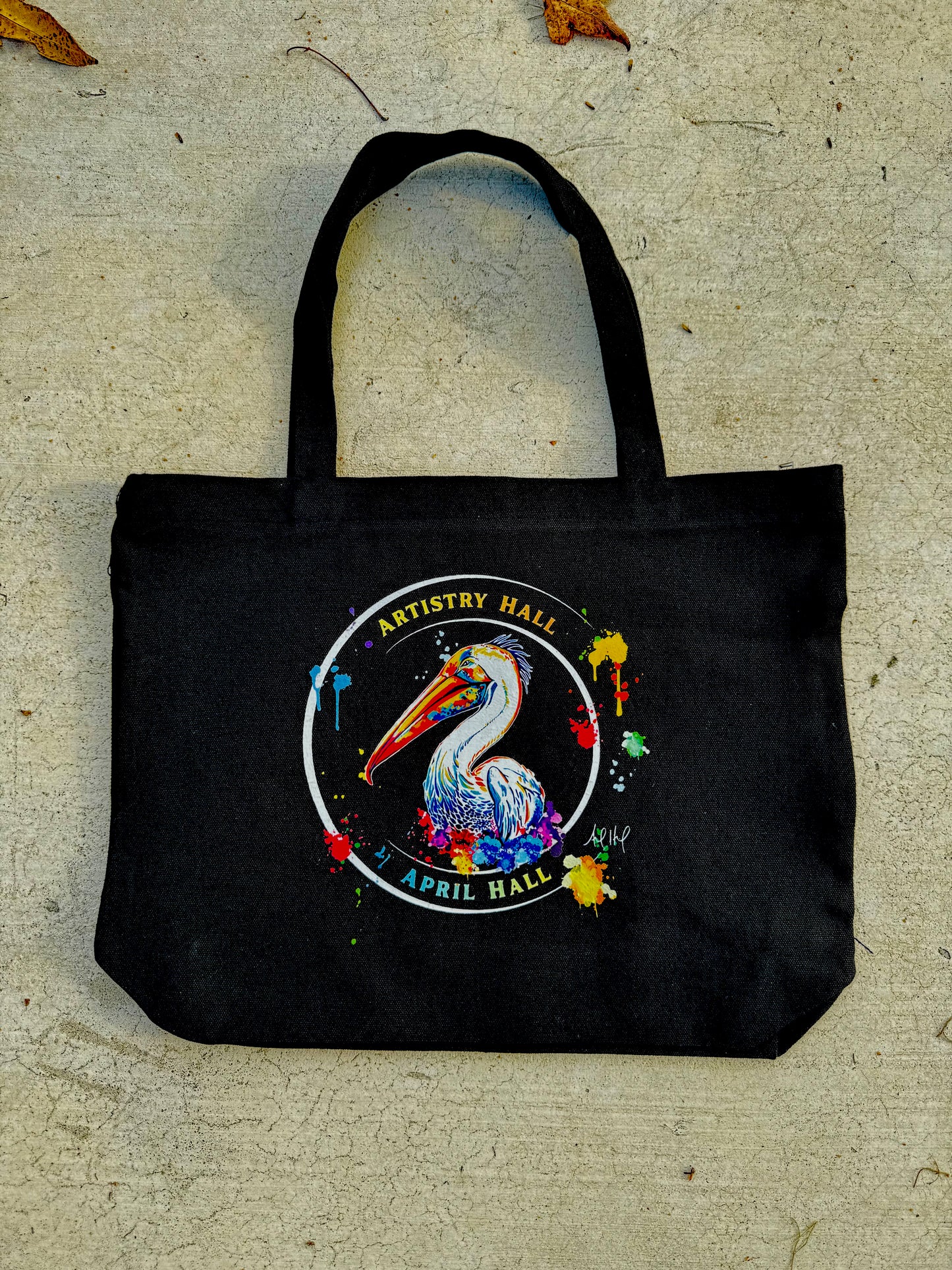 Black tote bag with Pelican design with the name "Artistry Hall" & artist "April Hall"